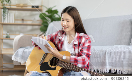 Asian woman specializes in music is composing the lyrics and melody for the opening of a new single, Using imagination and concentration in creating music, acoustic guitar, Creation of music notes. Asian woman specializes in music is composing the lyrics and melody for the opening of a new single, Using imagination and concentration in creating music, acoustic guitar, Creation of music notes. 96886245