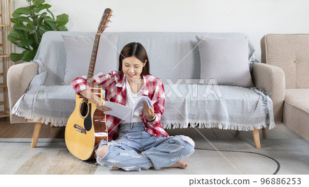 Asian woman specializes in music is composing the lyrics and melody for the opening of a new single, Using imagination and concentration in creating music, acoustic guitar, Creation of music notes. Asian woman specializes in music is composing the lyrics and melody for the opening of a new single, Using imagination and concentration in creating music, acoustic guitar, Creation of music notes. 96886253