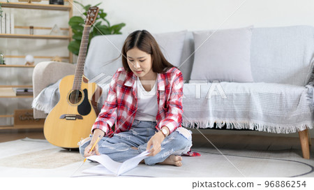 Asian woman specializes in music is composing the lyrics and melody for the opening of a new single, Using imagination and concentration in creating music, acoustic guitar, Creation of music notes. Asian woman specializes in music is composing the lyrics and melody for the opening of a new single, Using imagination and concentration in creating music, acoustic guitar, Creation of music notes. 96886254
