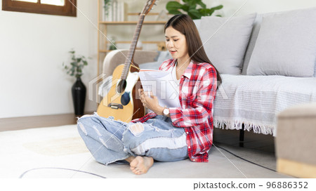 Asian woman specializes in music is composing the lyrics and melody for the opening of a new single, Using imagination and concentration in creating music, acoustic guitar, Creation of music notes. Asian woman specializes in music is composing the lyrics and melody for the opening of a new single, Using imagination and concentration in creating music, acoustic guitar, Creation of music notes. 96886352