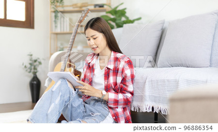 Asian woman specializes in music is composing the lyrics and melody for the opening of a new single, Using imagination and concentration in creating music, acoustic guitar, Creation of music notes. Asian woman specializes in music is composing the lyrics and melody for the opening of a new single, Using imagination and concentration in creating music, acoustic guitar, Creation of music notes. 96886354