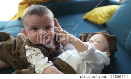 twin babies in retro clothes. brother and sister a twins kids sit on the couch in retro clothes lifestyle cap play among themselves. happy family kid dream twin concept twin babies in retro clothes. brother and sister a twins kids sit on the couch in retro clothes lifestyle cap play among themselves. happy family kid dream twin concept 96886534