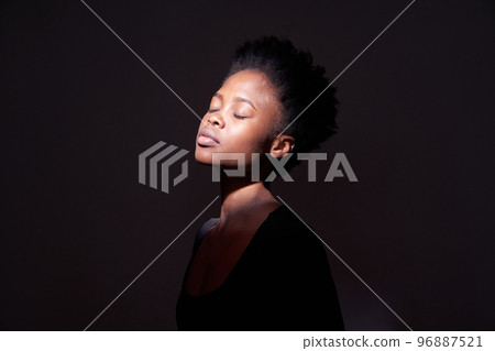A black woman showing emotions. A woman with an emotional expression and closed eyes on a black background with a ray of light on her face. With space to copy. High quality photo A black woman showing emotions. A woman with an emotional expression and closed eyes on a black background with a ray of light on her face. With space to copy. High quality photo 96887521