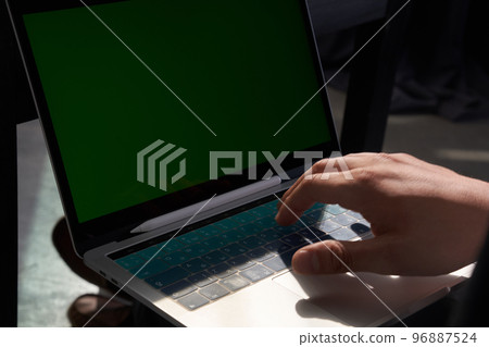 A man using a laptop with a colored green screen. Sunlight falls on the laptop keyboard. With space to copy. High quality photo A man using a laptop with a colored green screen. Sunlight falls on the laptop keyboard. With space to copy. High quality photo 96887524
