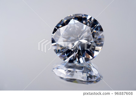 brilliant cut diamond held by tweezers on black background 96887608
