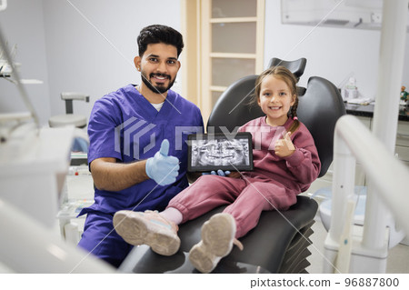 Caucasian preschool girl, sitting on dentist chair and looking at digital tablet with x-ray scan 96887800