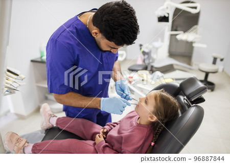 Confident bearded dentist examines the oral cavity of a young beautiful girl 96887844