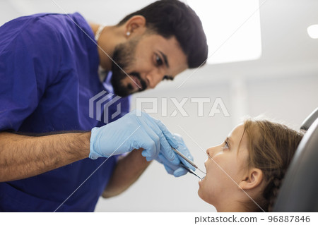 Doctor in uniform and gloves, making examination or curing caries and toothache for his patient 96887846