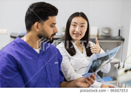 Attractive asian woman, sitting on dentist chair and looking at x-ray picture of scan image of teeth 96887853