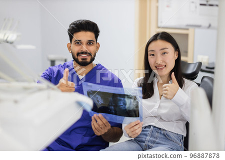 Smiling happy asian woman visiting dentist, sitting in dental chair at modern light hospital clinic. 96887878