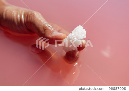 Hand holding salt crystal in pink water Nature spa 96887908