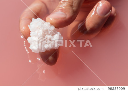 Hand holding salt crystal in pink water Nature spa Hand holding salt crystal in pink water Nature spa 96887909