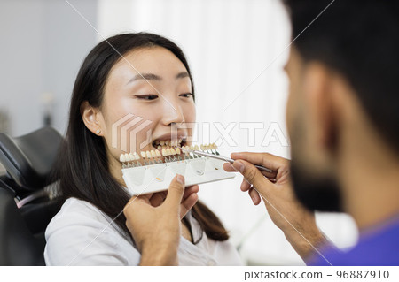 Dentist choosing color of filling from palette. 96887910