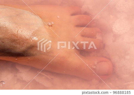 Woman foot in salt flakes in pink water, spa Woman foot in salt flakes in pink water, spa 96888185