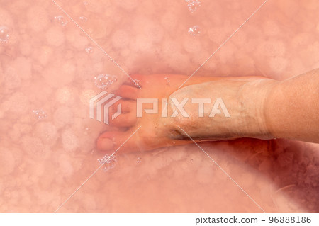 Woman foot in salt flakes in pink water, spa Woman foot in salt flakes in pink water, spa 96888186