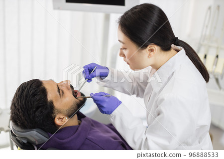 Young pretty asian doctor in white uniform and gloves, making examination or curing caries 96888533