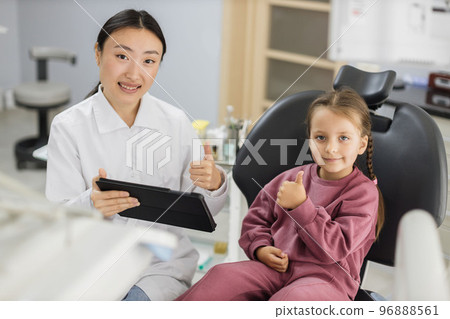 Happy female asian dentist and caucasian kid girl, having fun and showing thumbs up 96888561