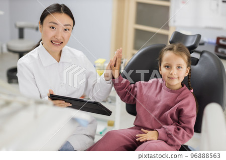Happy female asian dentist and caucasian kid girl, having fun and giving high five 96888563