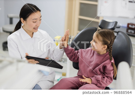 Happy female asian dentist and caucasian kid girl, having fun and giving high five 96888564