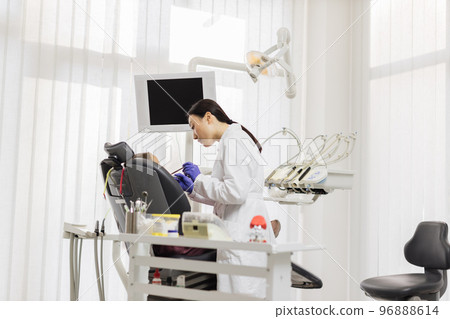Asian dentist treating teeth of a young beautiful girl using tooth drill Asian dentist treating teeth of a young beautiful girl using tooth drill 96888614