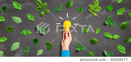 Person holding a lightbulb with green leaves 96888675