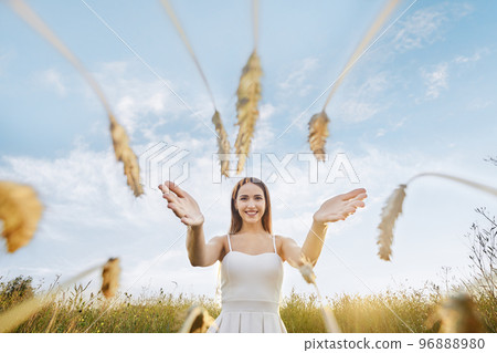 Happy woman stretches her hands to the ears of wheat Happy woman stretches her hands to the ears of wheat 96888980
