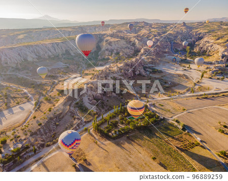 Colorful hot air balloons flying over at fairy chimneys valley in Nevsehir, Goreme, Cappadocia Turkey. Spectacular panoramic drone view of the underground city and ballooning tourism. High quality Colorful hot air balloons flying over at fairy chimneys valley in Nevsehir, Goreme, Cappadocia Turkey. Spectacular panoramic drone view of the underground city and ballooning tourism. High quality 96889259