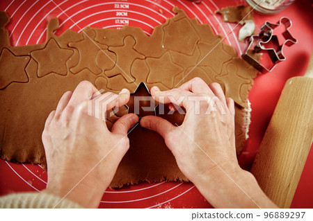 Female hands cutting figures from ginger dough with cutter. Cooking gingerbread cookies to preparing for winter holidays. Christmas baking 96889297
