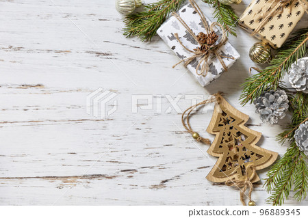 Christmas gold decor, fir tree twigs and gifts box on a white wood background. View from above. Copy space. Christmas gold decor, fir tree twigs and gifts box on a white wood background. View from above. Copy space. 96889345