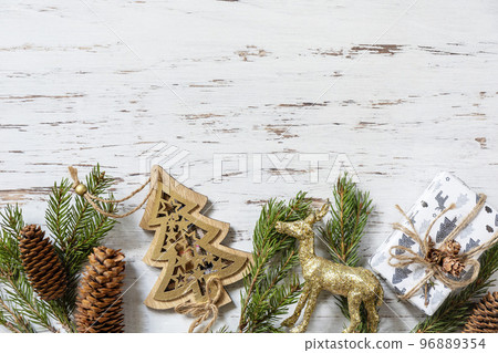 Christmas gold decor, christmas deer, fir tree twigs and gifts box on a white wood background. View from above. Copy space. 96889354