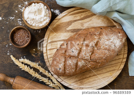 Bread from whole wheat grains, wheat bran, seeds, bio-ingredients over rustic table background. Homemade baking, healthy lifestyle. View from above. Bread from whole wheat grains, wheat bran, seeds, bio-ingredients over rustic table background. Homemade baking, healthy lifestyle. View from above. 96889389
