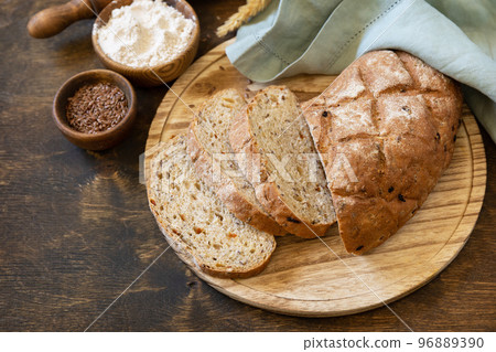 Homemade baking. Bread from whole wheat grains, wheat bran, seeds, bio-ingredients over rustic table background, healthy lifestyle. Copy space. Homemade baking. Bread from whole wheat grains, wheat bran, seeds, bio-ingredients over rustic table background, healthy lifestyle. Copy space. 96889390