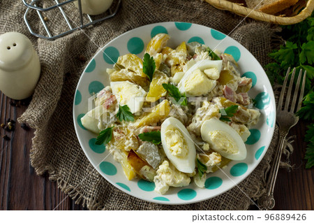 Salad with baked potatoes, pickled cucumber, egg and smoked turkey on a festive table in a rustic style. Salad with baked potatoes, pickled cucumber, egg and smoked turkey on a festive table in a rustic style. 96889426