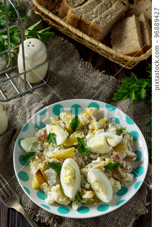 Salad with baked potatoes, pickled cucumber, egg and smoked turkey on a festive table in a rustic style. Salad with baked potatoes, pickled cucumber, egg and smoked turkey on a festive table in a rustic style. 96889427