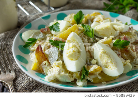 Salad with baked potatoes, pickled cucumber, egg and smoked turkey close-up on a festive table in a rustic style. Salad with baked potatoes, pickled cucumber, egg and smoked turkey close-up on a festive table in a rustic style. 96889429
