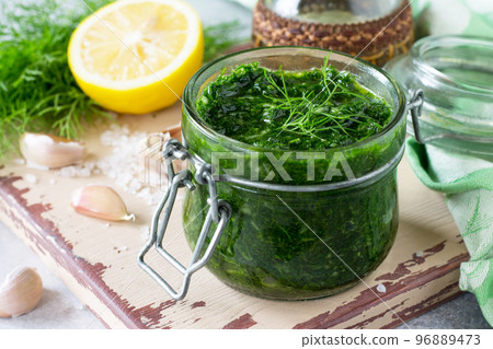 Preserving dill with garlic and olive oil on the kitchen wooden background. Preserving dill with garlic and olive oil on the kitchen wooden background. 96889473
