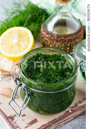 Preserving sauce dill with garlic and olive oil on the kitchen wooden background. Preserving sauce dill with garlic and olive oil on the kitchen wooden background. 96889474