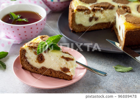 Cheesecake and mint tea cup. Chocolate New York cheesecake and mint tea cup on concrete background. Cheesecake and mint tea cup. Chocolate New York cheesecake and mint tea cup on concrete background. 96889478
