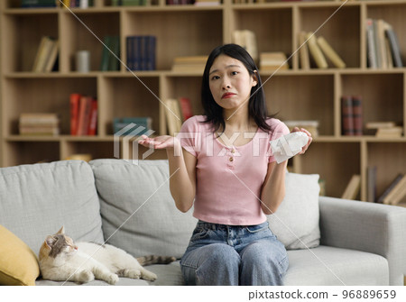 Upset korean lady holding paper tissue, having allergic to fur and suffering from running nose caused by her pet cat 96889659
