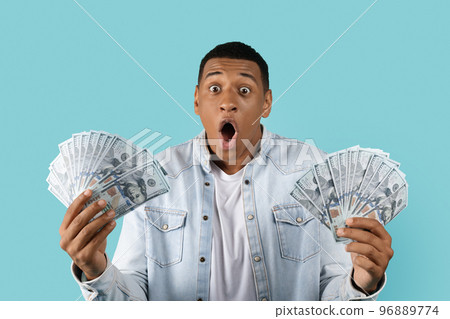 Shocked glad excited funny young african american man with open mouth look at many dollars in hands 96889774
