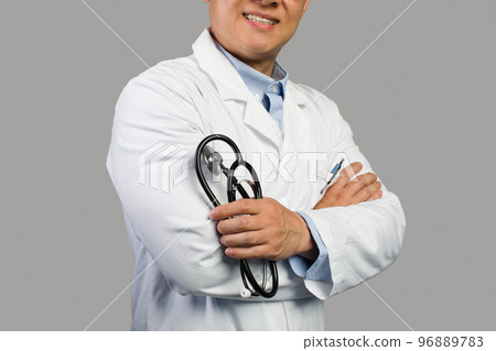 Smiling confident adult chinese male therapist in white coat with stethoscope, isolated on gray background 96889783