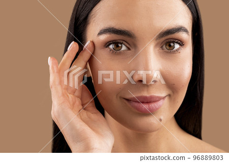 Pretty attractive brunette millennial lady touching wrinkles near temples, closeup Pretty attractive brunette millennial lady touching wrinkles near temples, closeup 96889803