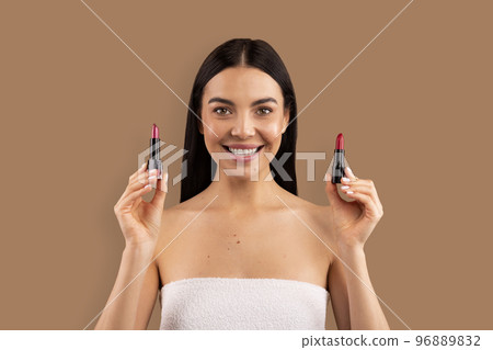 Attractive brunette young woman holding two lipsticks 96889832