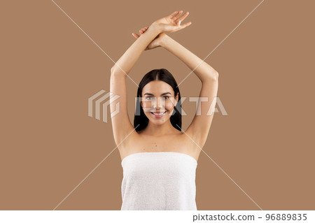Beautiful half-naked woman with hands up posing on beige 96889835