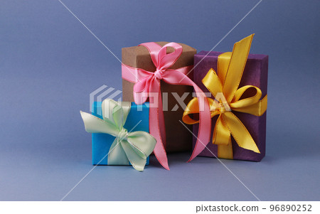 Three multicolored gift boxes on blue background. 96890252