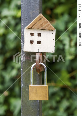 Wooden house model a on a closed gate with a padlock. Home privacy and security concept Wooden house model a on a closed gate with a padlock. Home privacy and security concept 96891251