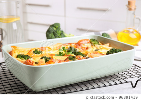 Tasty broccoli casserole in baking dish on cooling rack indoors 96891419
