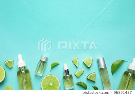 Flat lay composition with lime essential oil on light turquoise background. Space for text 96891487