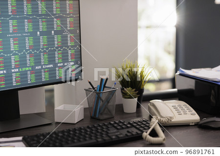Partial view of computer monitor with financial analysis software for stock market investment risk. Investment specialist desk with work materials on the table early in the morning. 96891761