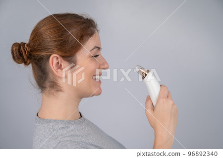 Caucasian woman uses a vacuum pore cleaner at home. Caucasian woman uses a vacuum pore cleaner at home. 96892340